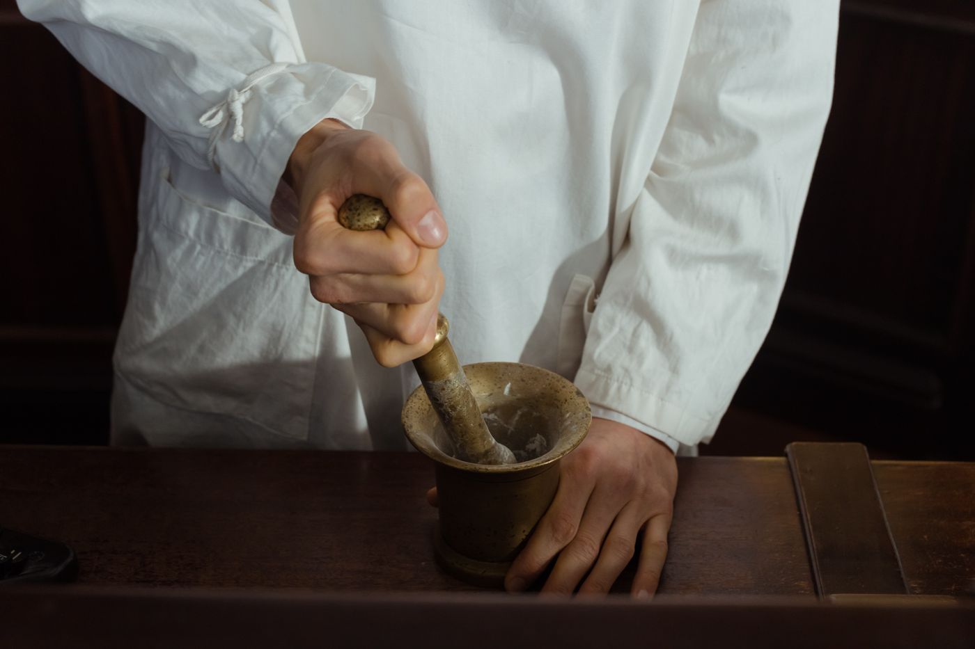 A pharmacist grinding a compounded medication with a mortar and pestle